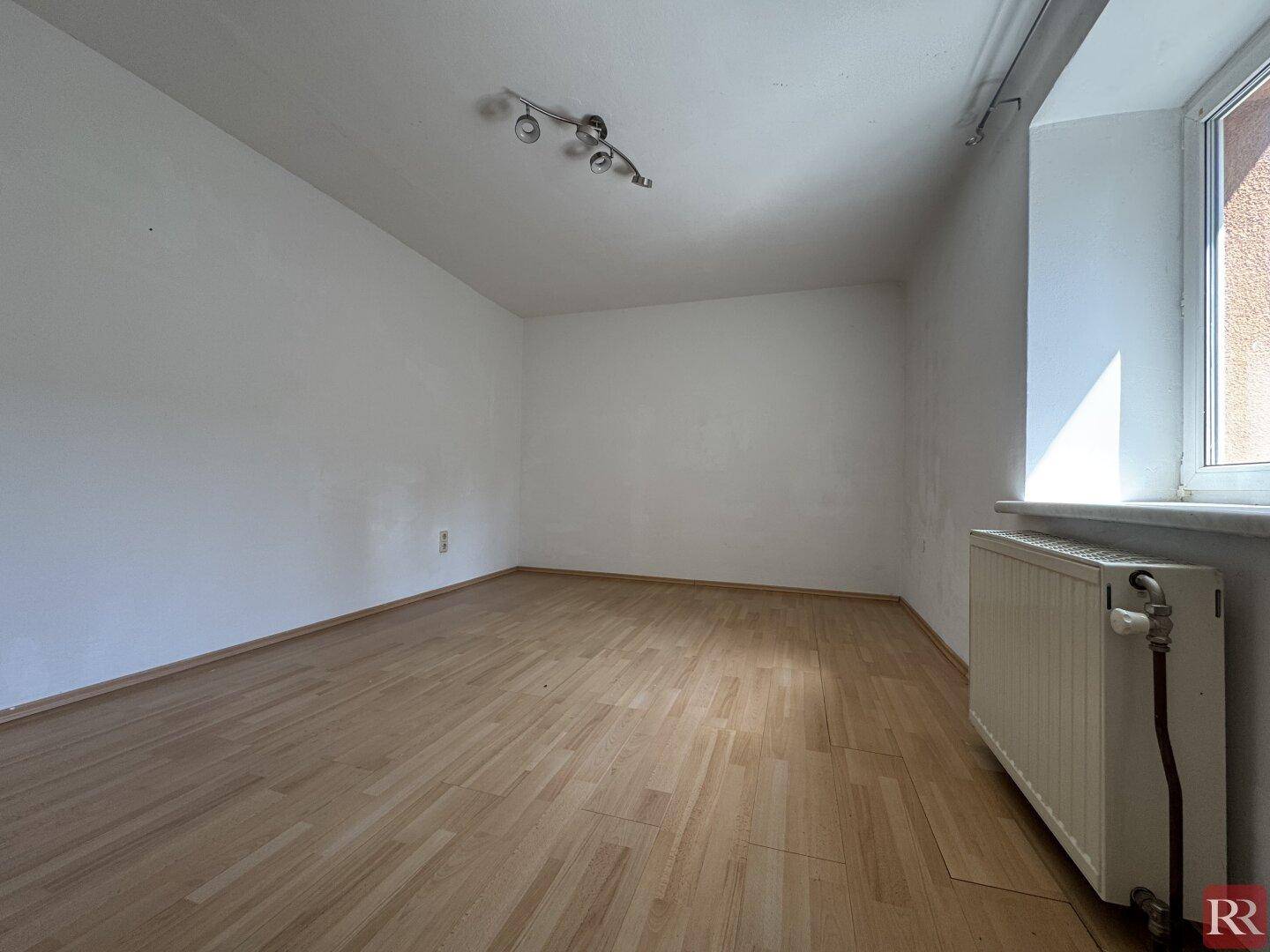 Heller, leerer Raum mit Laminatboden und weißen Wänden, ideal für individuelle Einrichtung.