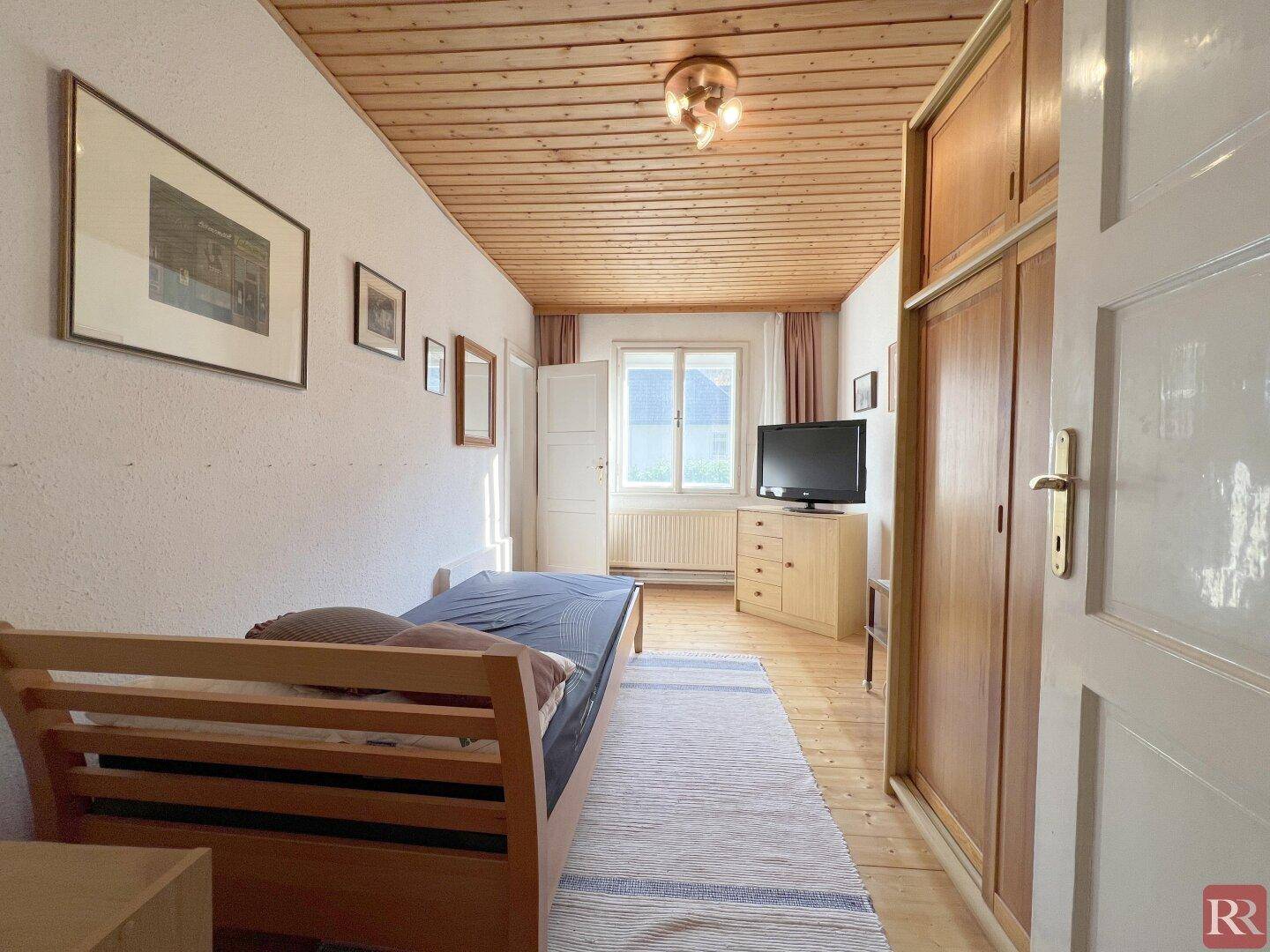Gemütliches Schlafzimmer mit Holzboden, Holzdecke und Einbauschrank, hell und funktional.