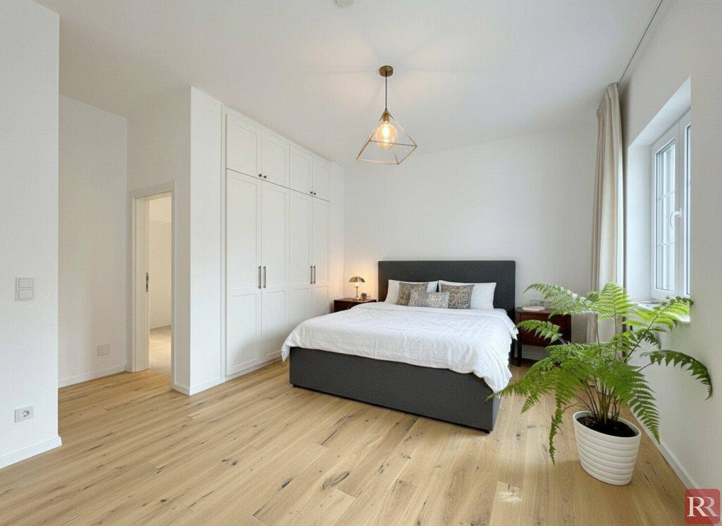 Helles Schlafzimmer mit Doppelbett, Einbauschränken und Parkettboden.