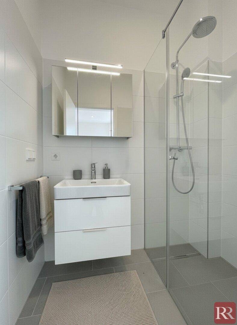 Kompaktes Badezimmer mit moderner Dusche, Waschtisch und Spiegelschrank.