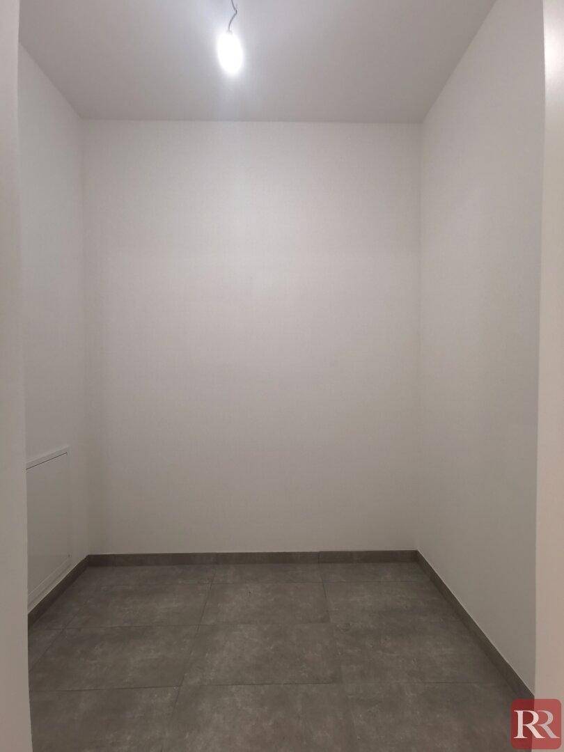 Kleiner, leerer Raum mit grauen Fliesen und weißen Wänden, ideal als Abstellraum.