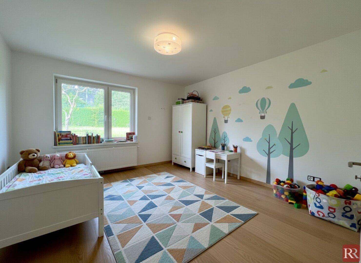 Kinderzimmer mit Holzboden, Fenster und spielerischer Wanddekoration.
