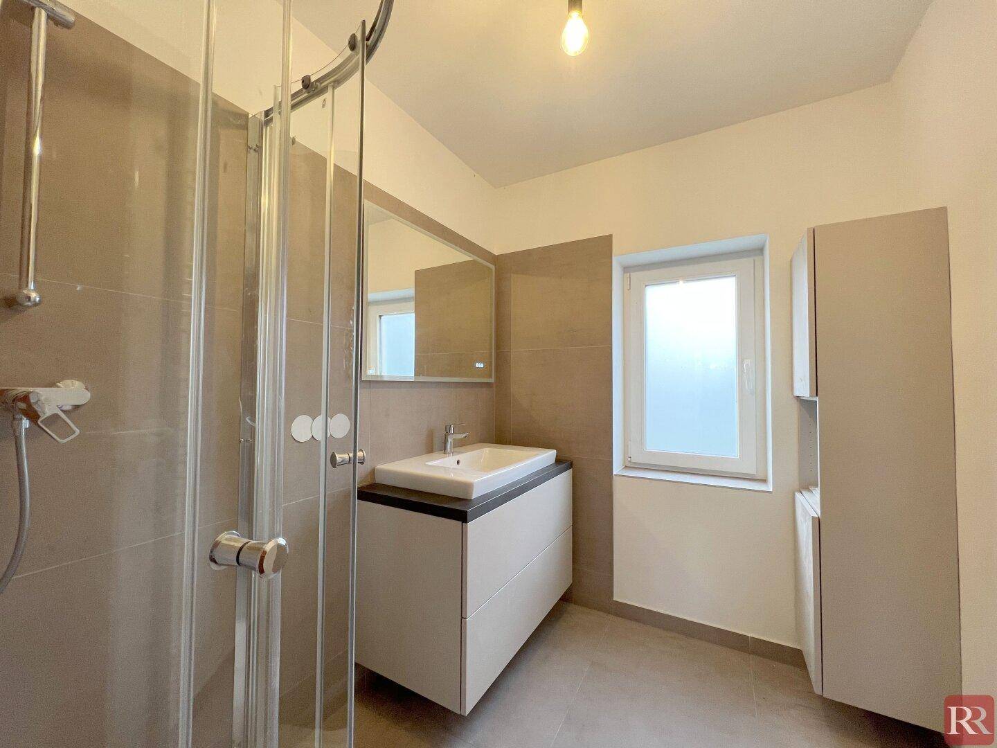Modernes Badezimmer mit Duschkabine, Einzelwaschbecken und Fenster.