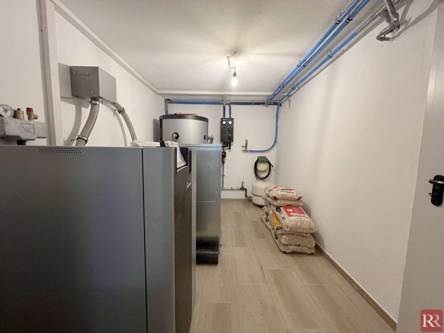 Heizraum im Keller mit Heizungsanlagen und sichtbaren Rohrleitungen.