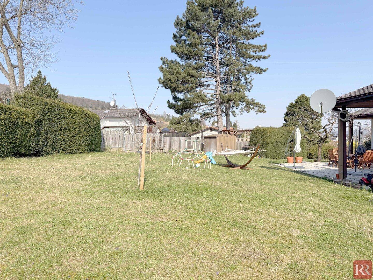 Großer, gepflegter Garten mit Rasenfläche, Bäumen und Hängematte.