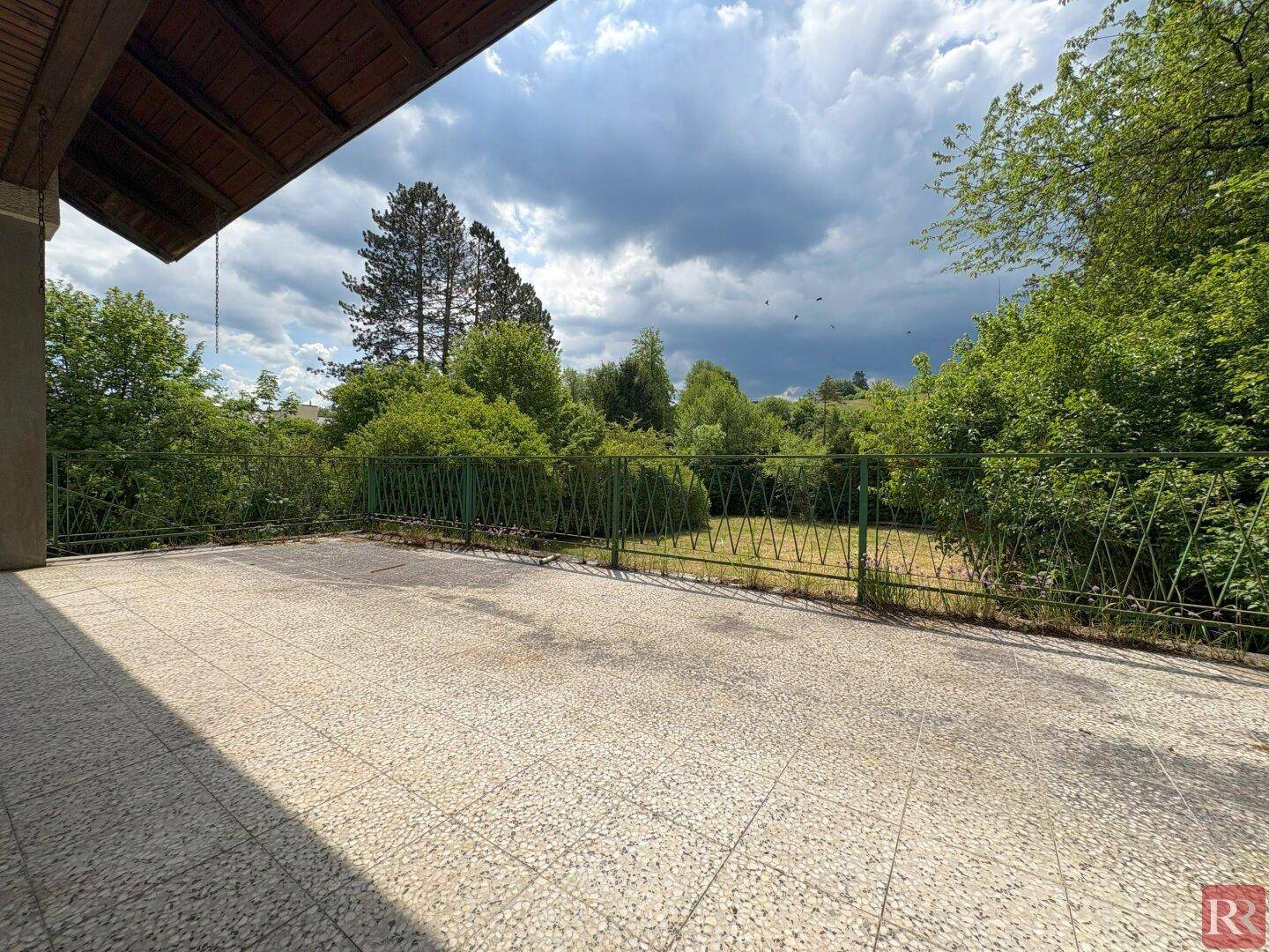 Große geflieste Terrasse mit Blick auf die umliegende Natur und den Garten.
