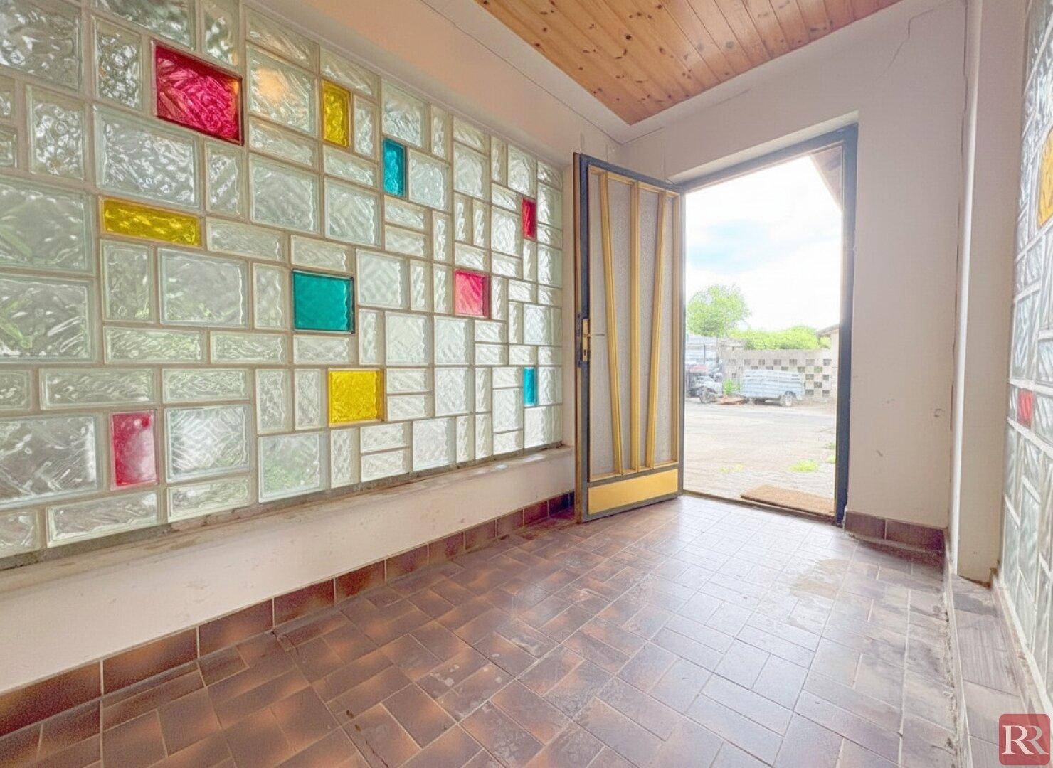 Heller Eingangsbereich mit farbigen Glasbausteinen und gefliestem Boden.