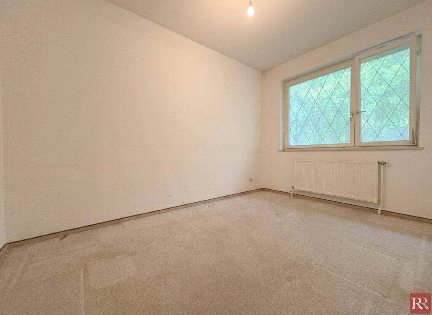 Helles Schlafzimmer mit Teppichboden und großem Fenster, ideal für persönliche Einrichtung.