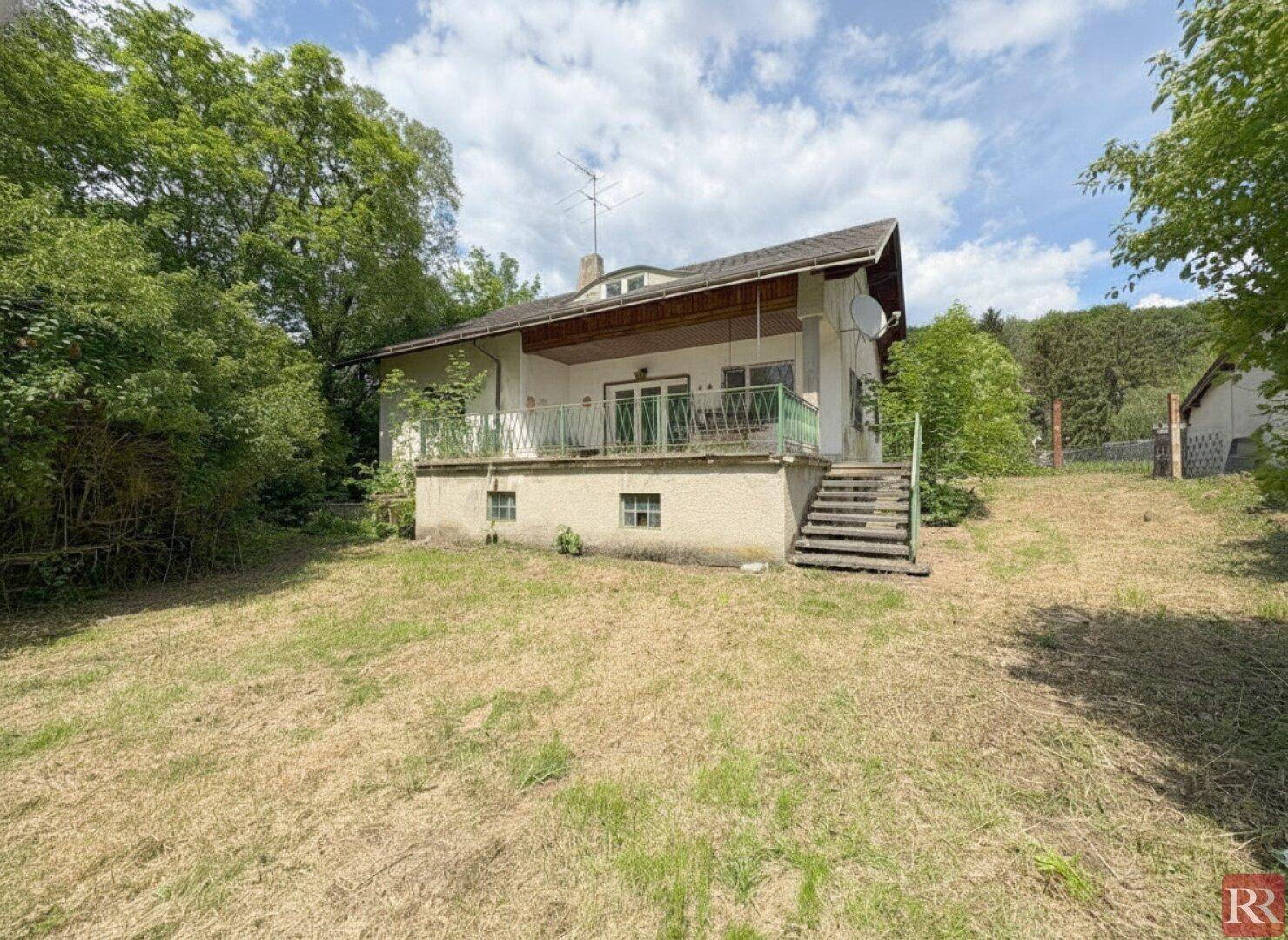 Rückansicht des Hauses mit Balkon, Treppe zum Garten und weitem Blick ins Grüne.
