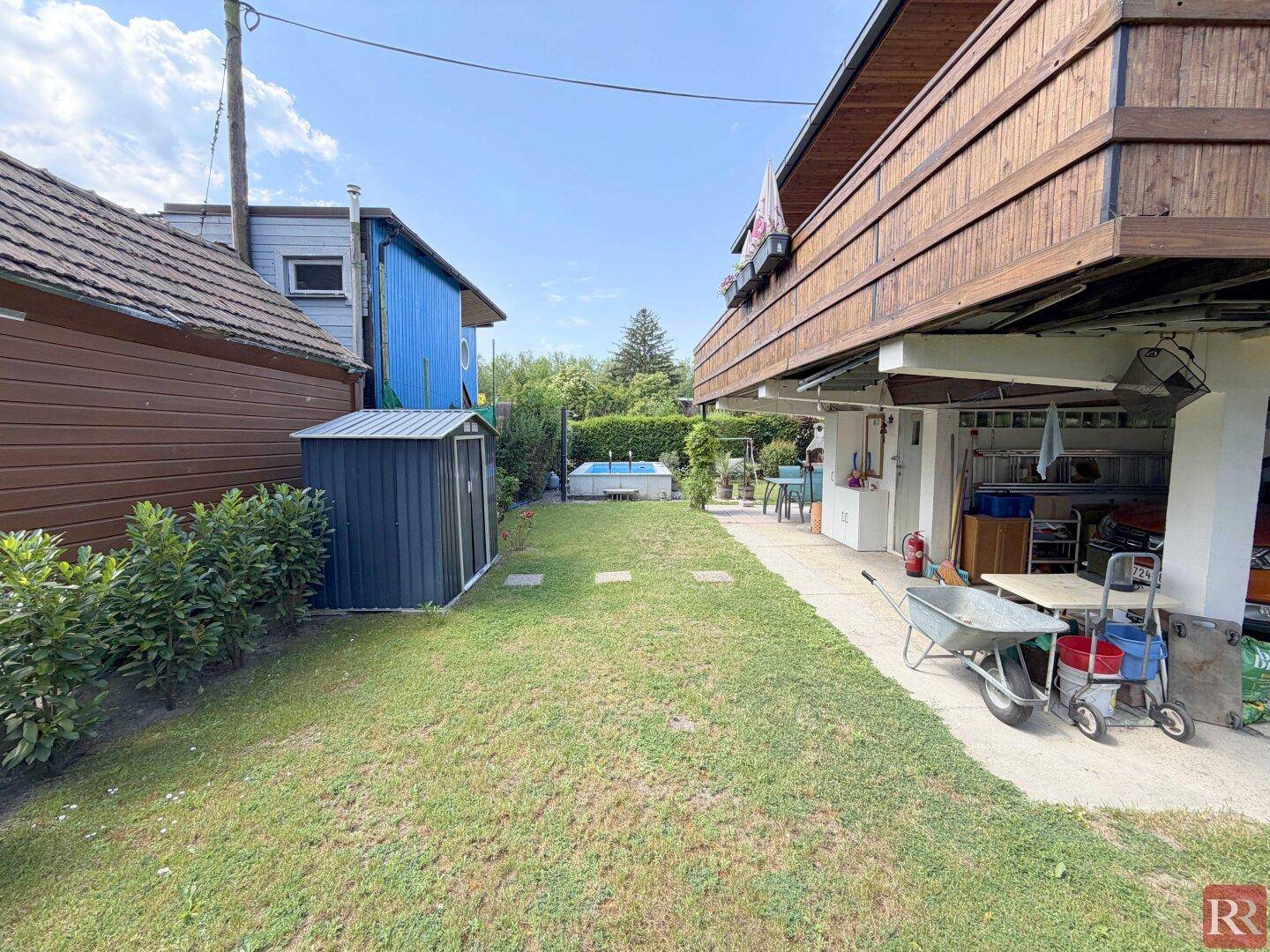 Gepflegter Gartenbereich mit Rasen, kleinem Pool und Zugang zum überdachten Untergeschoss.