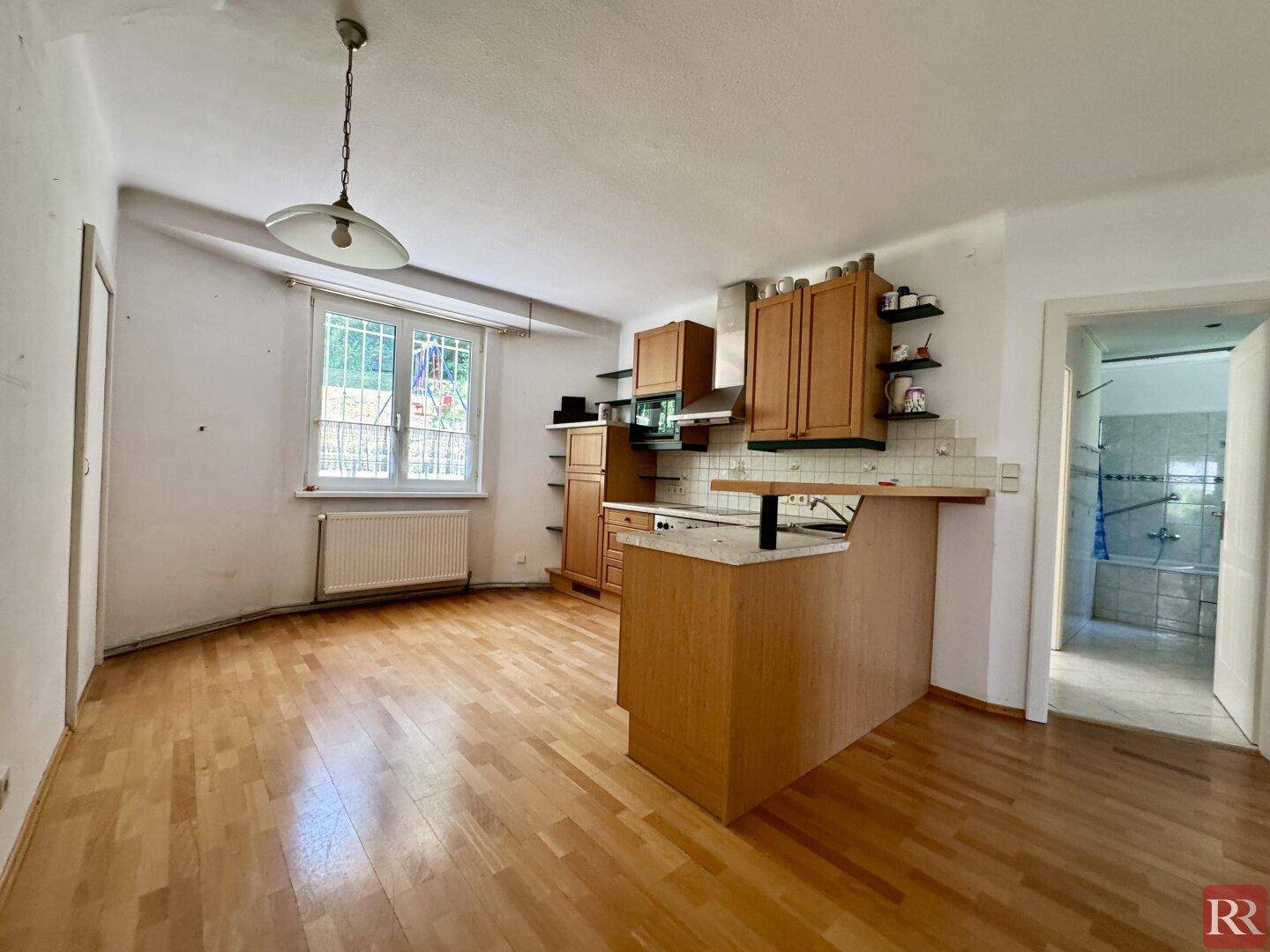 Funktionale Küche mit Holzschränken, integrierten Geräten und einer Frühstücksbar, offen zum Essbereich.
