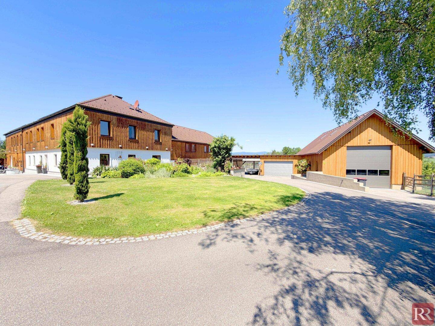 Ansicht des Anwesens mit gepflegtem Vorgarten, Zufahrt und separatem Garagengebäude.