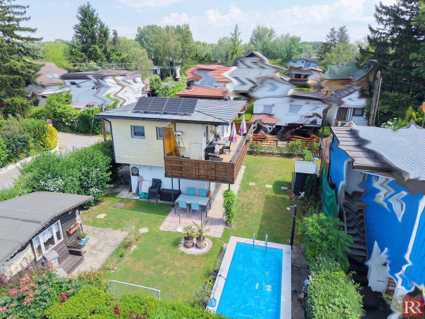 Sonniges Haus mit großem Holzbalkon, überdachtem Pool und gepflegtem Garten.