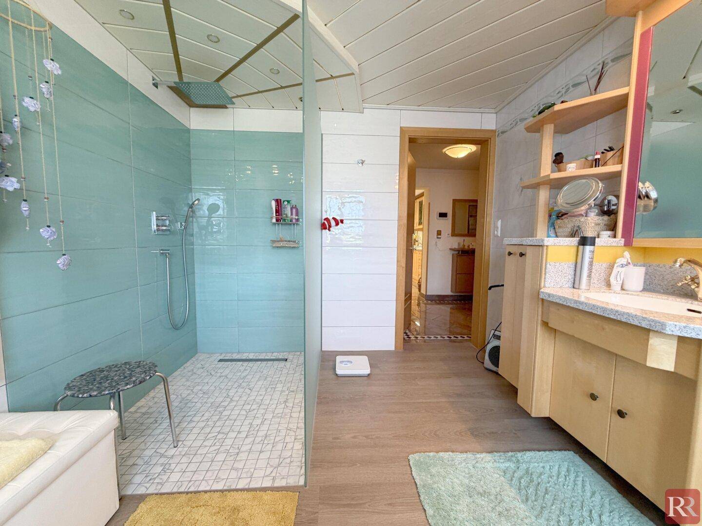 Modernes Badezimmer mit begehbarer Dusche, Holzdecke und Einzelwaschbecken auf Holzfußboden.