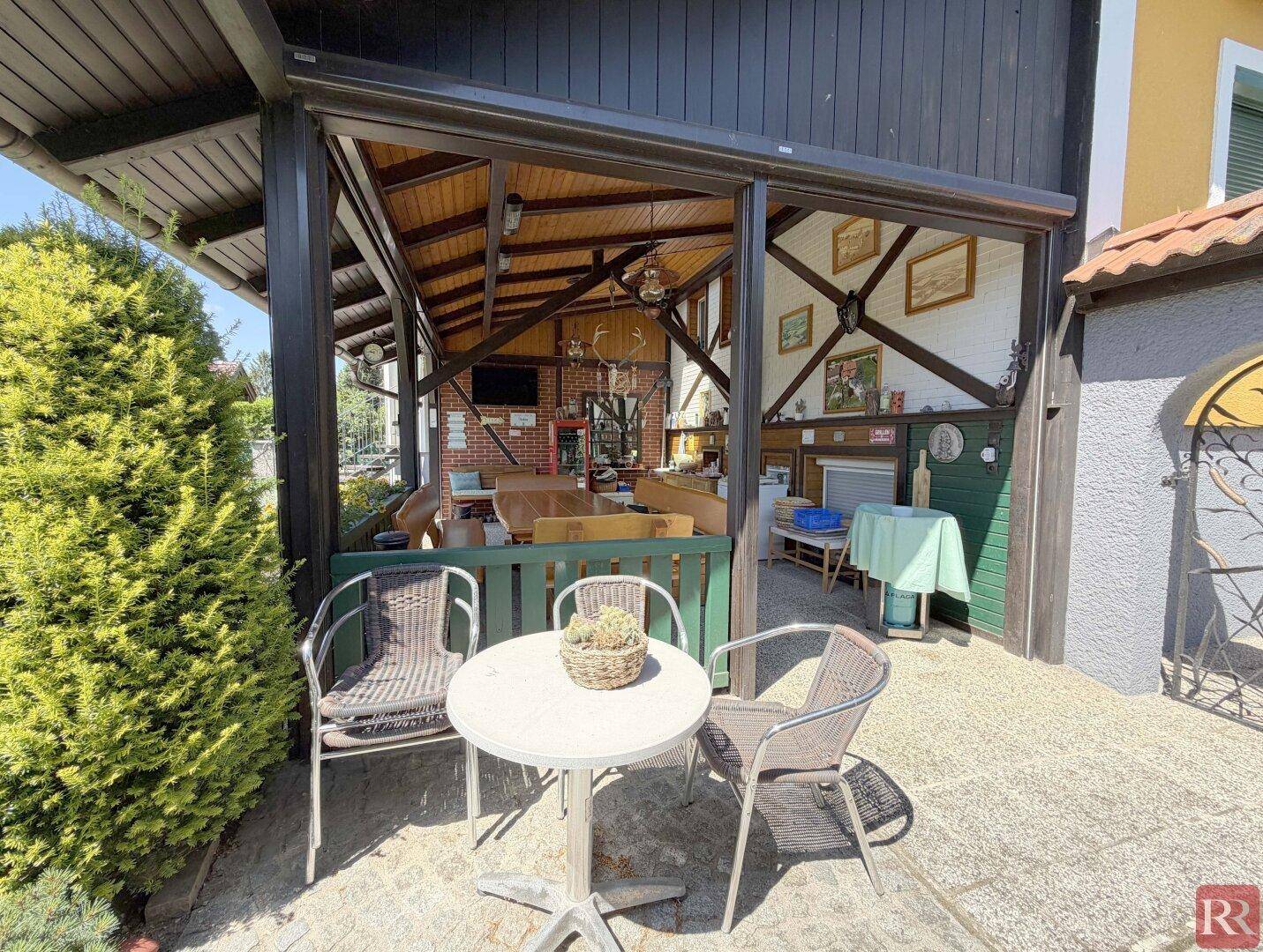 Gemütlicher Außenbereich mit kleinem Tisch und Stühlen unter der Terrassenüberdachung.