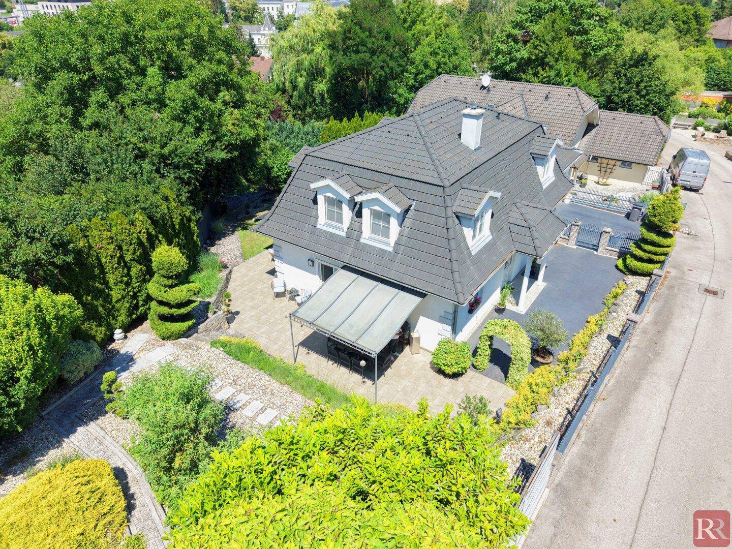 Luftaufnahme des Einfamilienhauses mit großem Garten, Terrasse und gepflegter Umgebung.