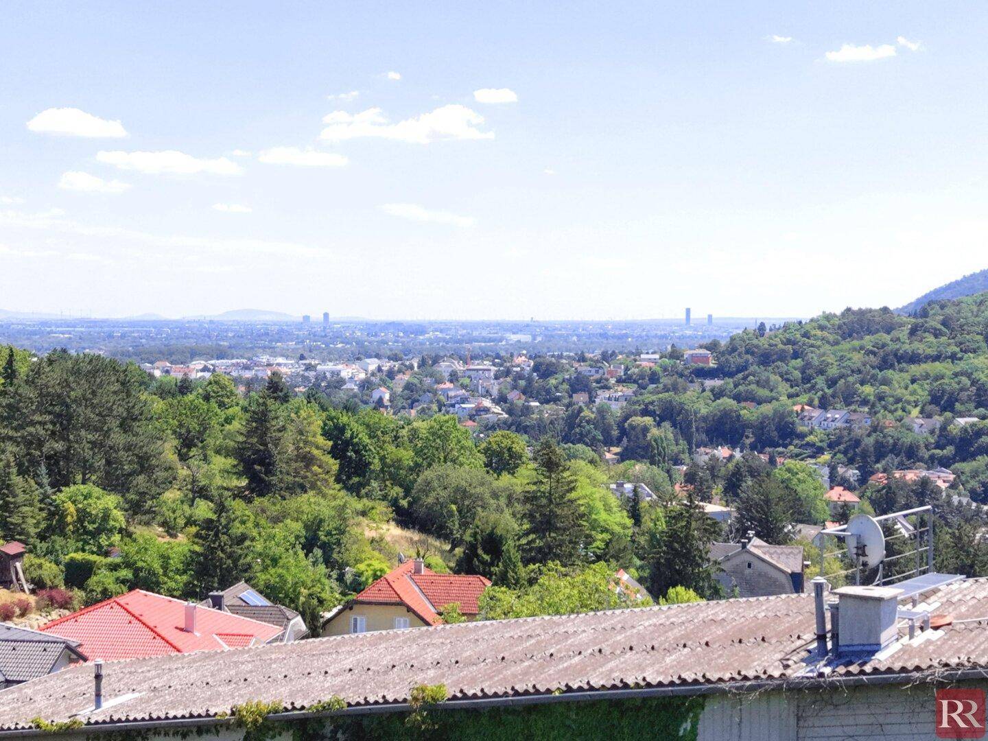 Weitläufiger Panoramablick über die Stadt und die umliegende grüne Landschaft von einem Hügel aus.