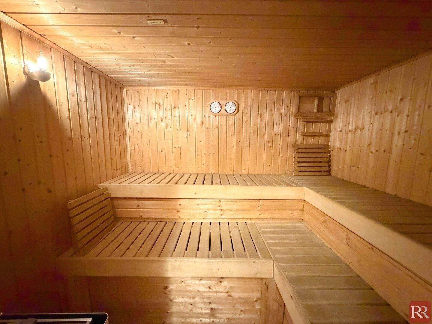 Innenansicht einer geräumigen Holzsauna mit mehrstufigen Sitzbänken.