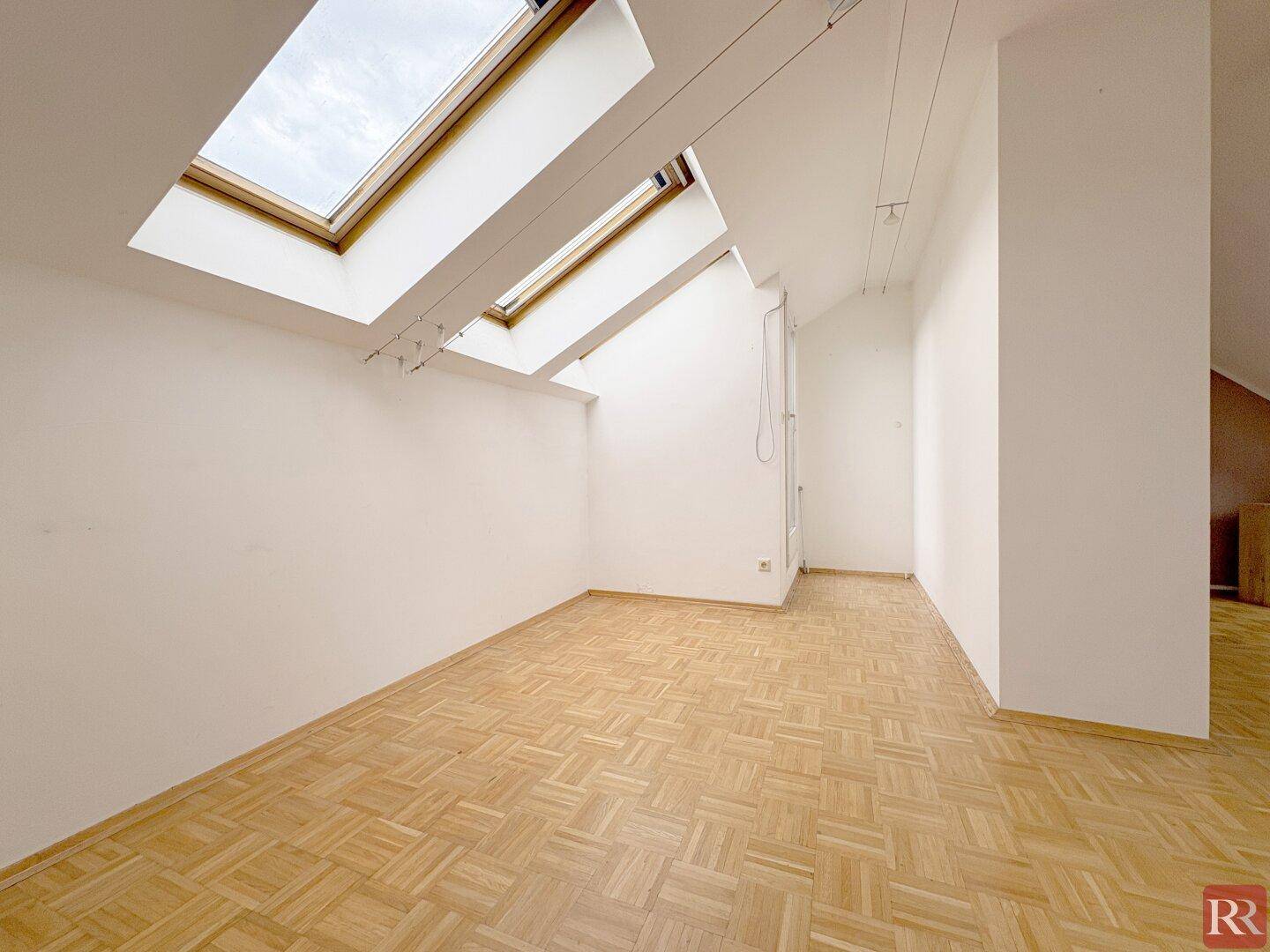 Helles Zimmer mit Parkettboden und zwei großen Dachfenstern, die für eine ausgezeichnete natürliche Belichtung sorgen.
