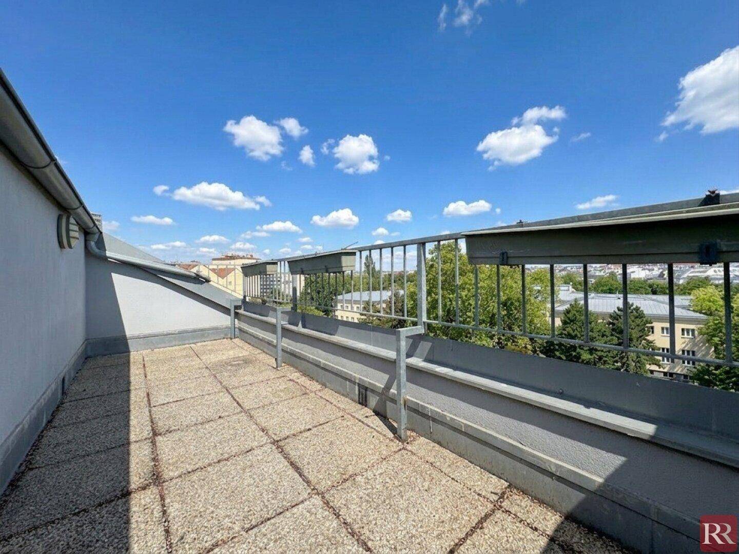 Geräumige Dachterrasse mit Fliesenboden und Metallgeländer, ideal zum Entspannen mit Stadtblick.