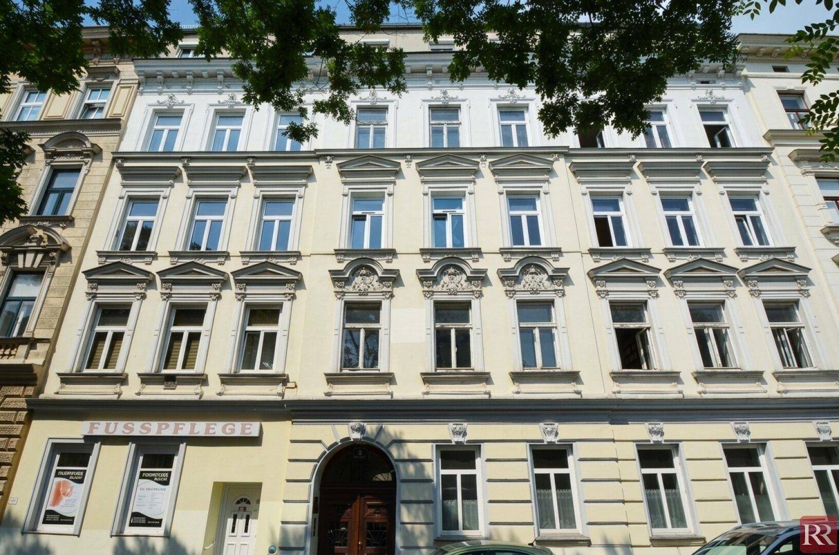Klassische Fassade eines Altbaus mit vielen Fenstern und dekorativen architektonischen Details.