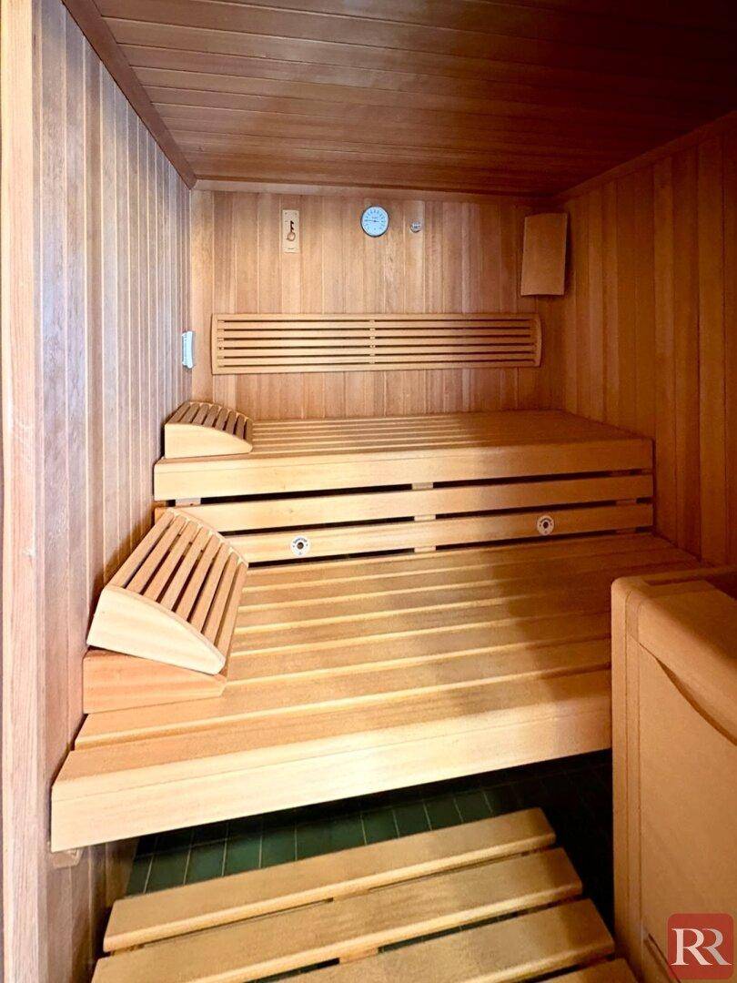 Gemütliche Holzsauna mit mehreren Bänken und integriertem Thermometer für Entspannung.