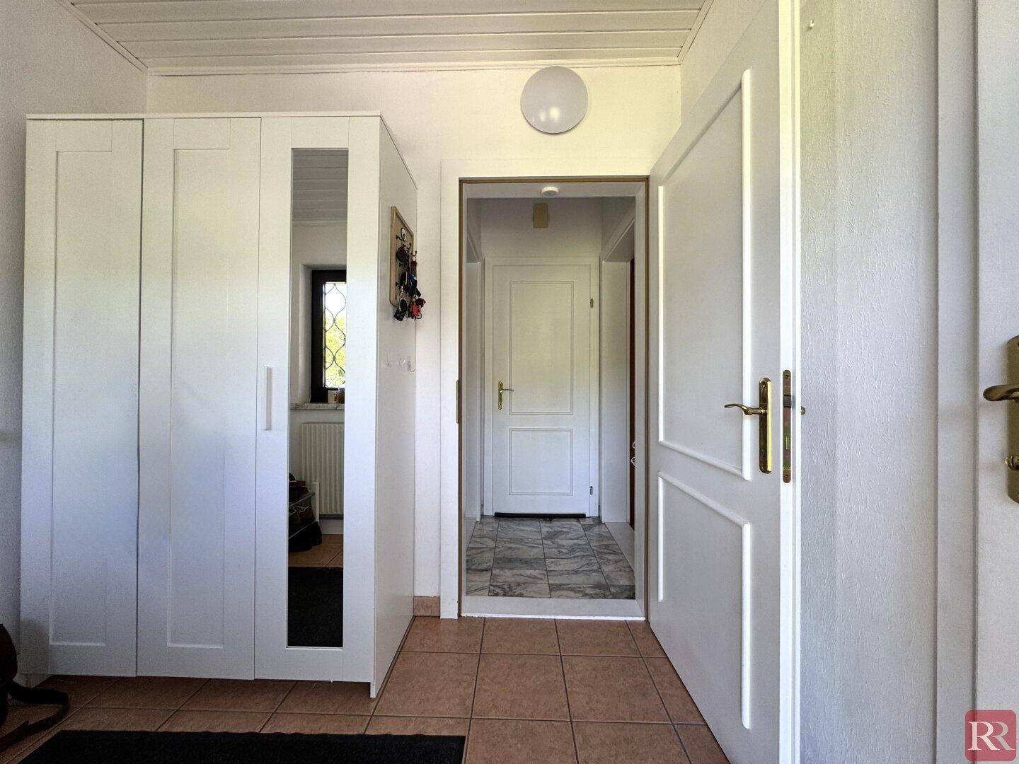 Heller Eingangsbereich mit Terrakotta-Fliesenboden und Spiegelschrank.