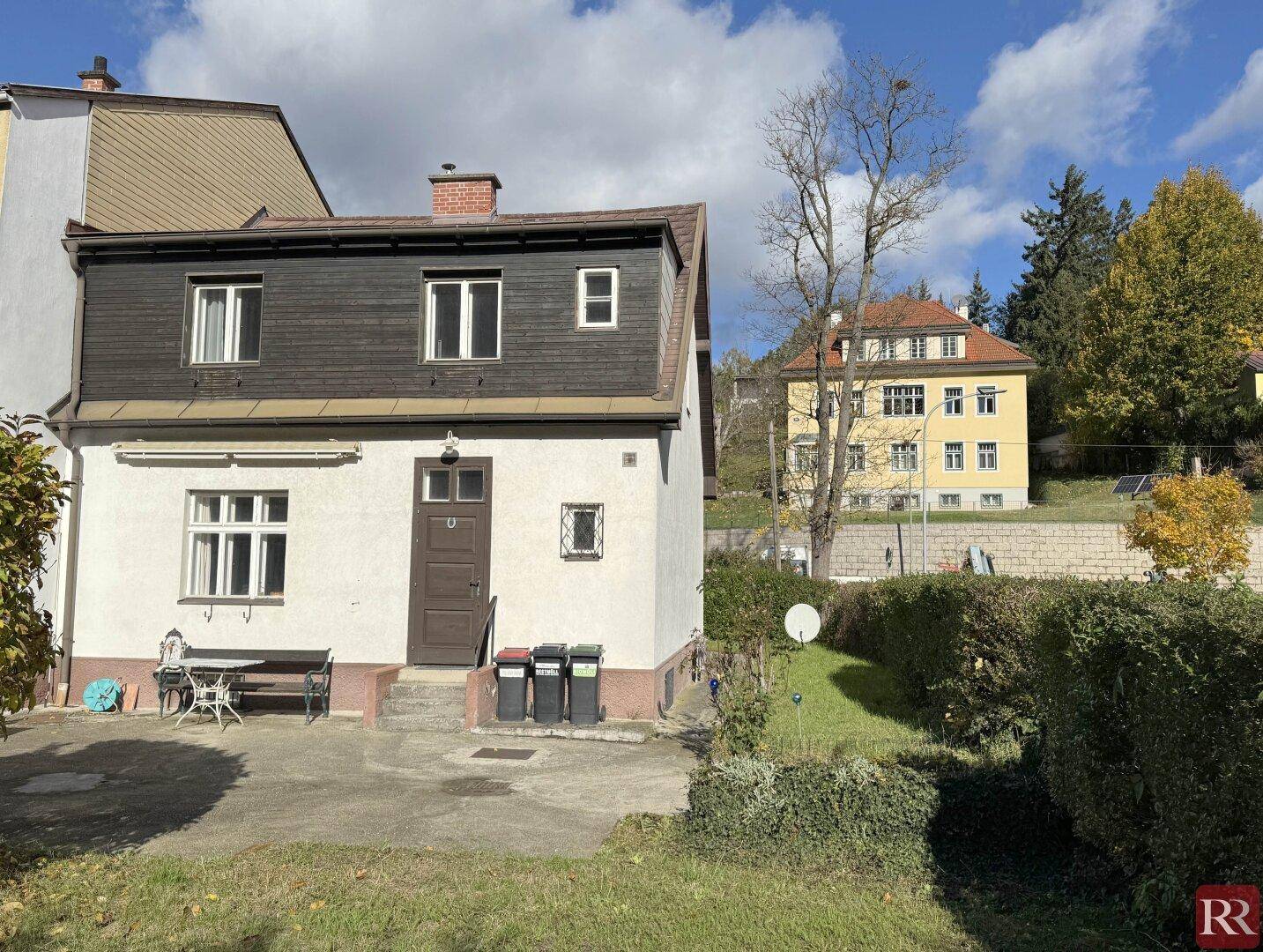 Rückansicht des Hauses mit Garten und kleiner Terrasse an einem sonnigen Herbsttag.