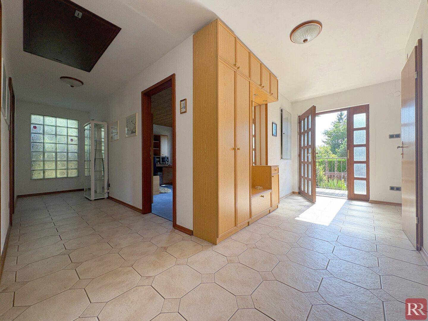 Heller Eingangsbereich mit Fliesenboden, Einbauschränken und Zugang zum Balkon.
