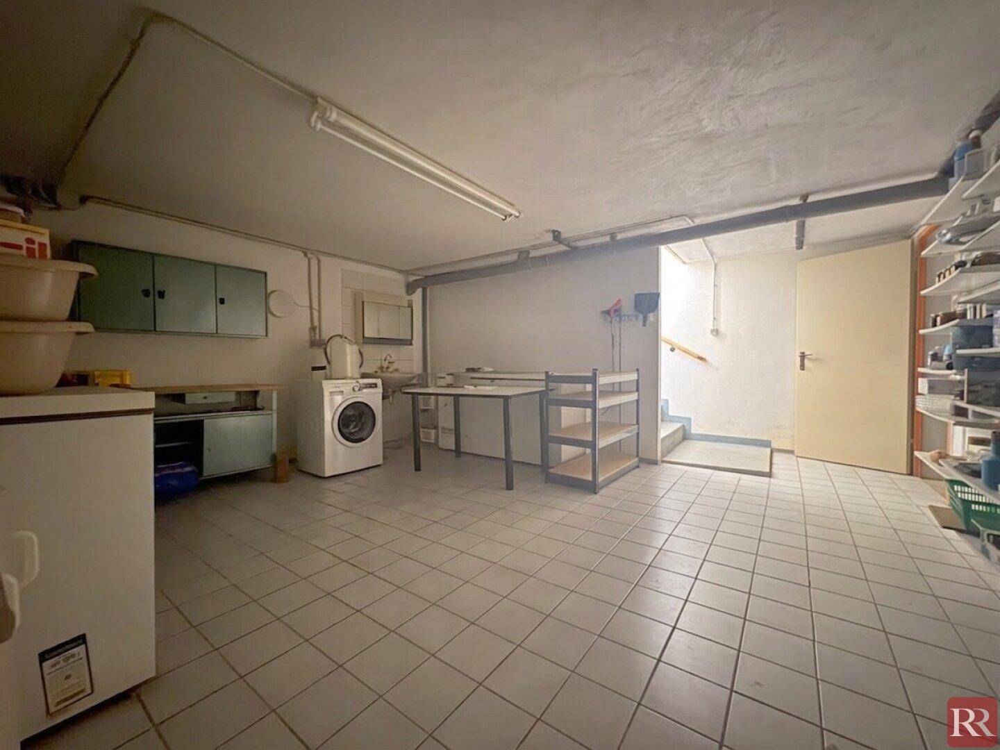 Geräumiger Hauswirtschaftsraum im Keller mit Waschmaschine und Lagerregalen.