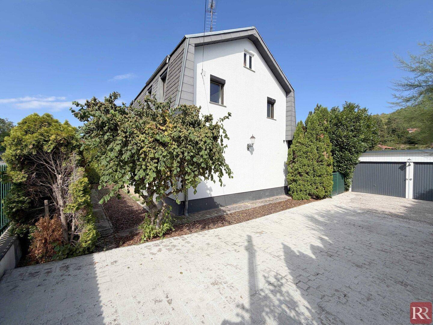 Seitenansicht des Hauses mit gepflasterter Auffahrt und angrenzender Garage.