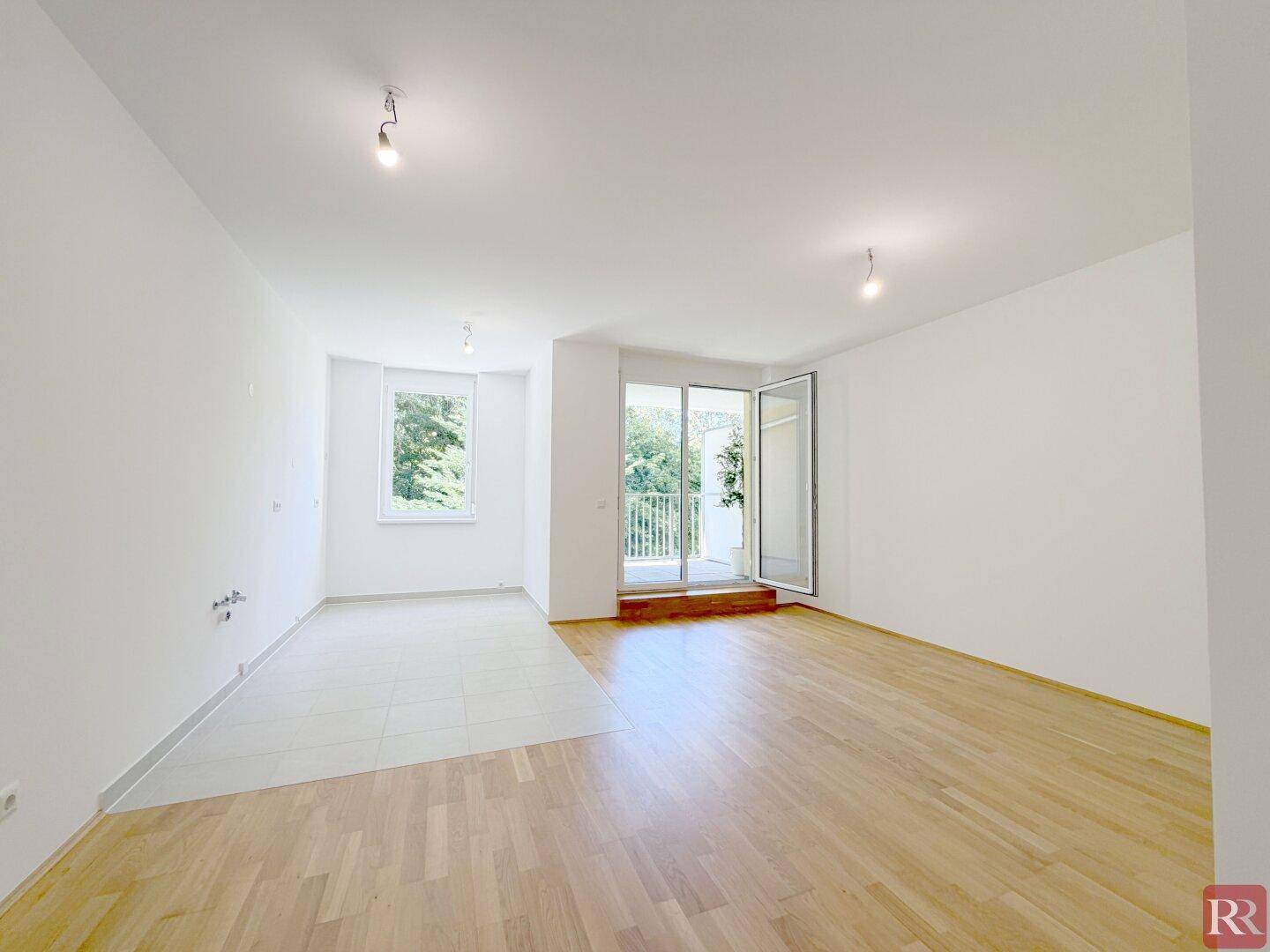 Geräumiger Wohnraum mit hellem Parkett und Fliesenbereich, ideal für offenes Wohnen.