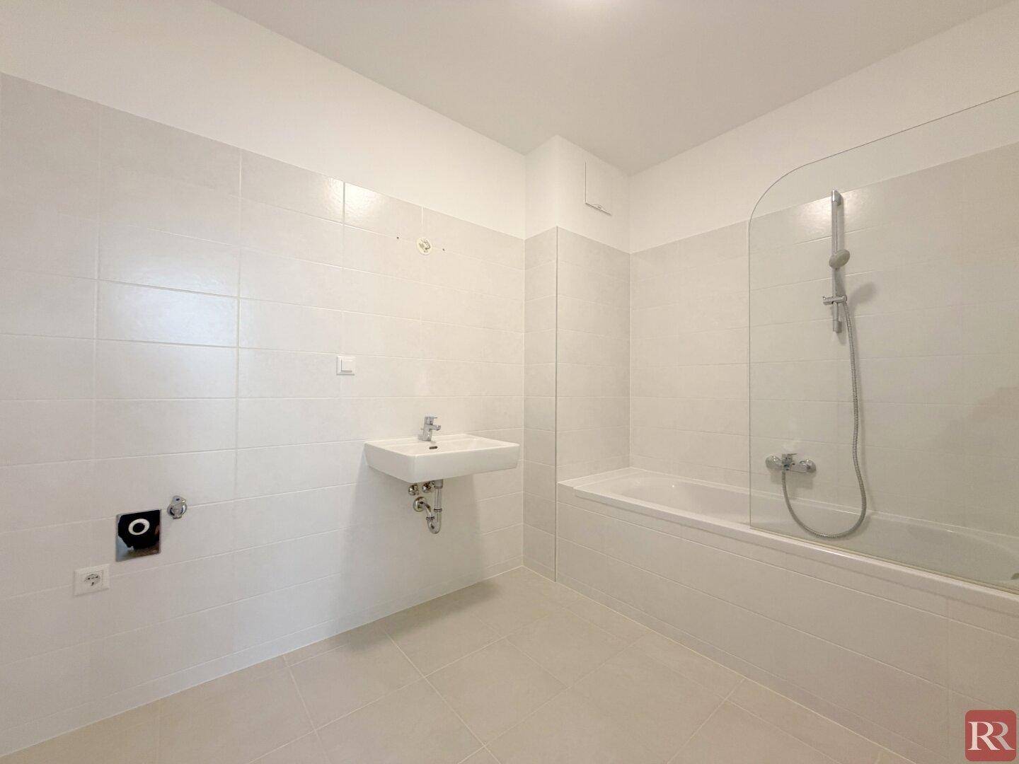 Modernes Badezimmer mit weißen Fliesen, Badewanne und einem einzelnen Waschbecken.