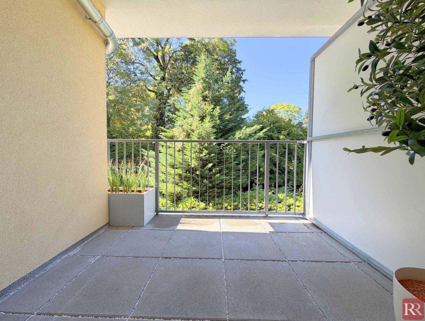 Geräumiger Balkon mit Fliesenboden und Blick auf die grüne Umgebung, ideal zum Entspannen.