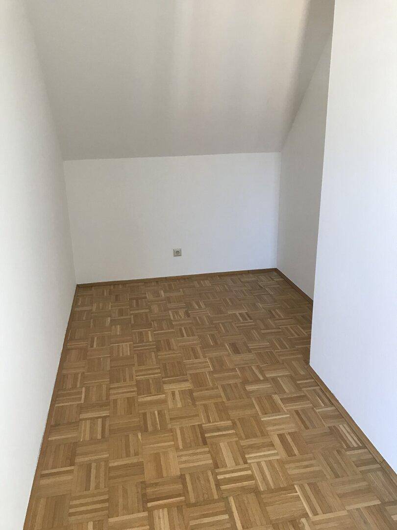 Kleiner, heller Raum mit Parkettboden und Dachschrägen, ideal als Schlaf- oder Arbeitszimmer.