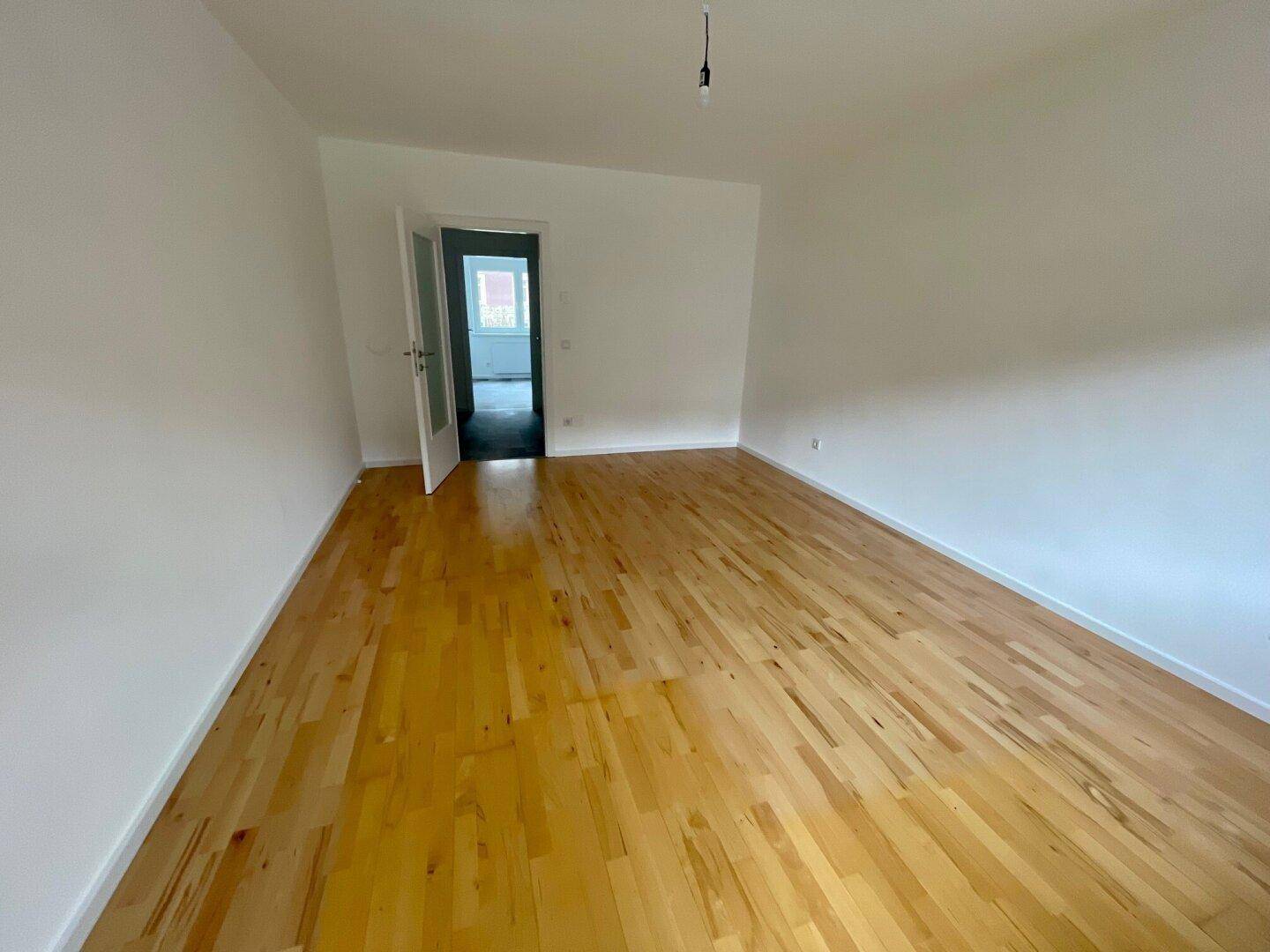 Heller, leerer Raum mit schönem Holzboden und weiß gestrichenen Wänden, ideal für individuelle Gestaltung.
