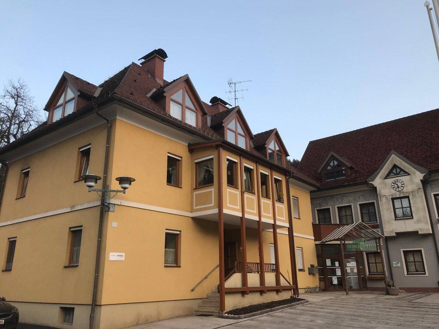 Gelbes Gebäude mit traditionellem Satteldach und Gaubenfenstern in ländlicher Umgebung.