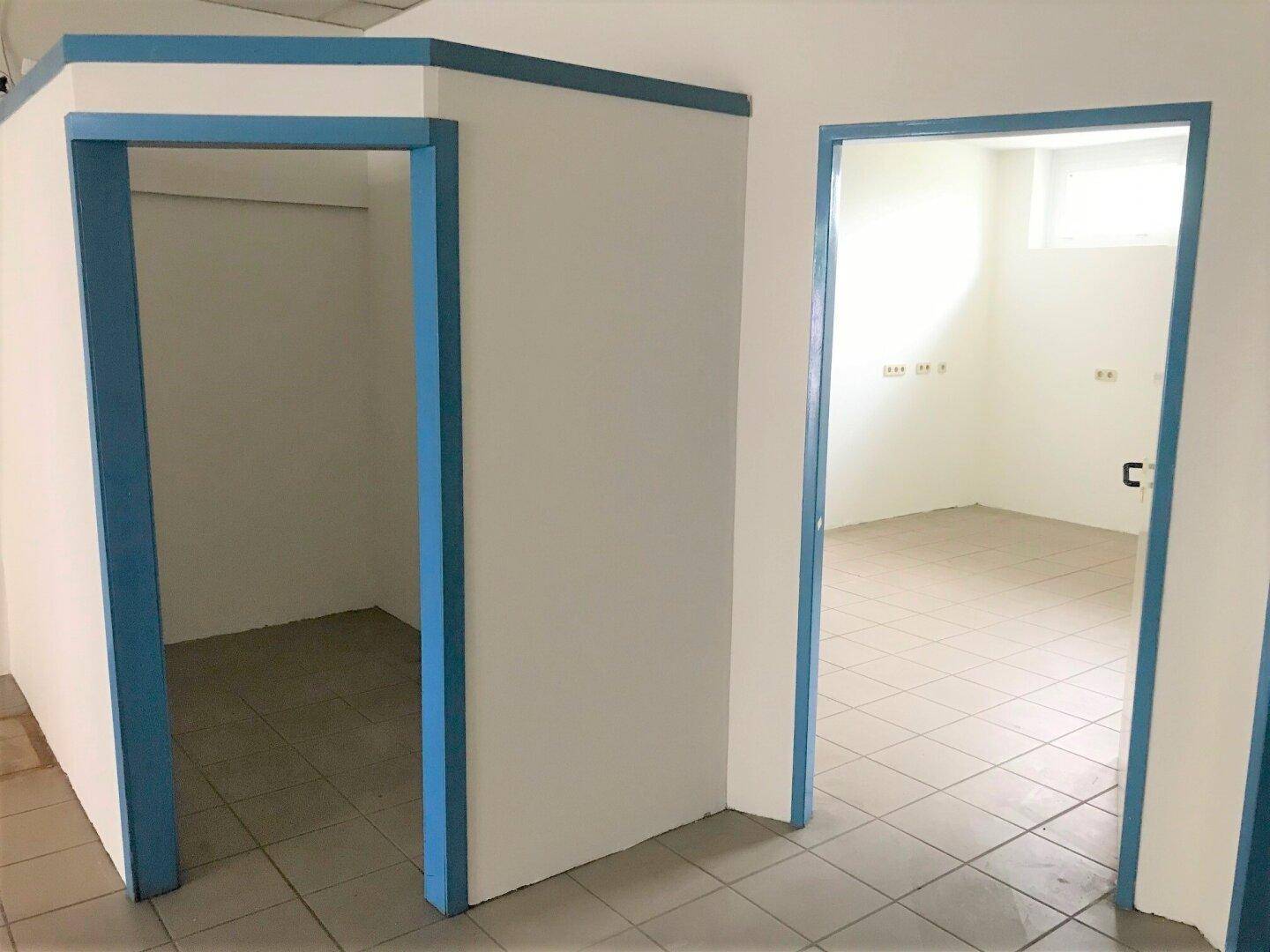 Innenansicht mit blauen Türrahmen und Fliesenboden, die zu einem weiteren Raum führt.