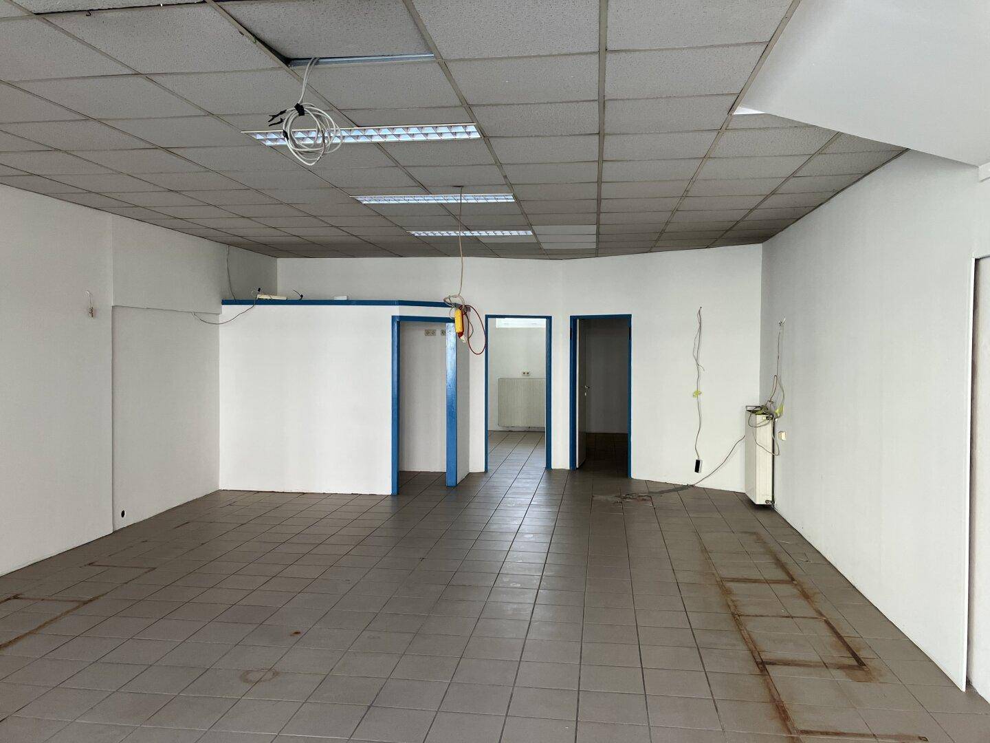Hinterer Bereich des Gewerberaums mit mehreren Türen und einem Fliesenboden, bereit für die Gestaltung.