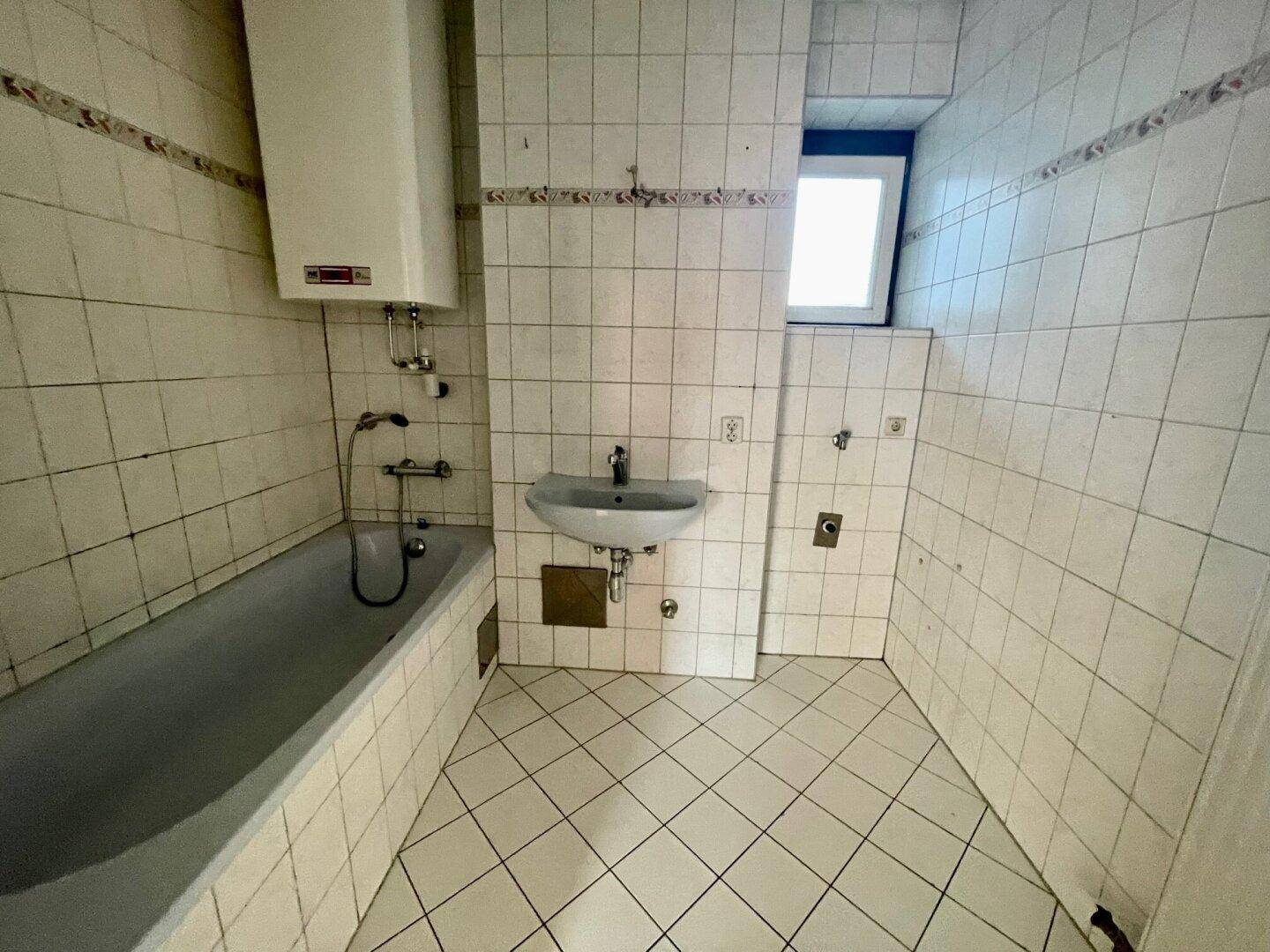 Badezimmer mit Badewanne, Waschbecken und Fliesen im 80er-Jahre-Stil.