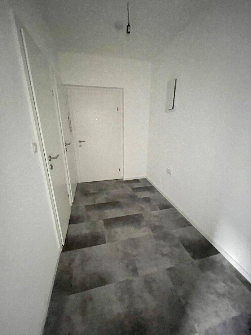 Heller Flur mit weißen Wänden und modernem Vinylboden.