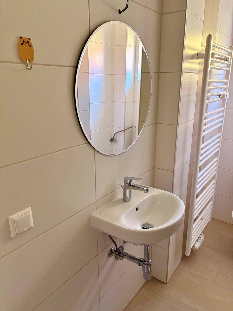 Modernes Badezimmer mit Waschbecken, Spiegel und beheiztem Handtuchhalter.