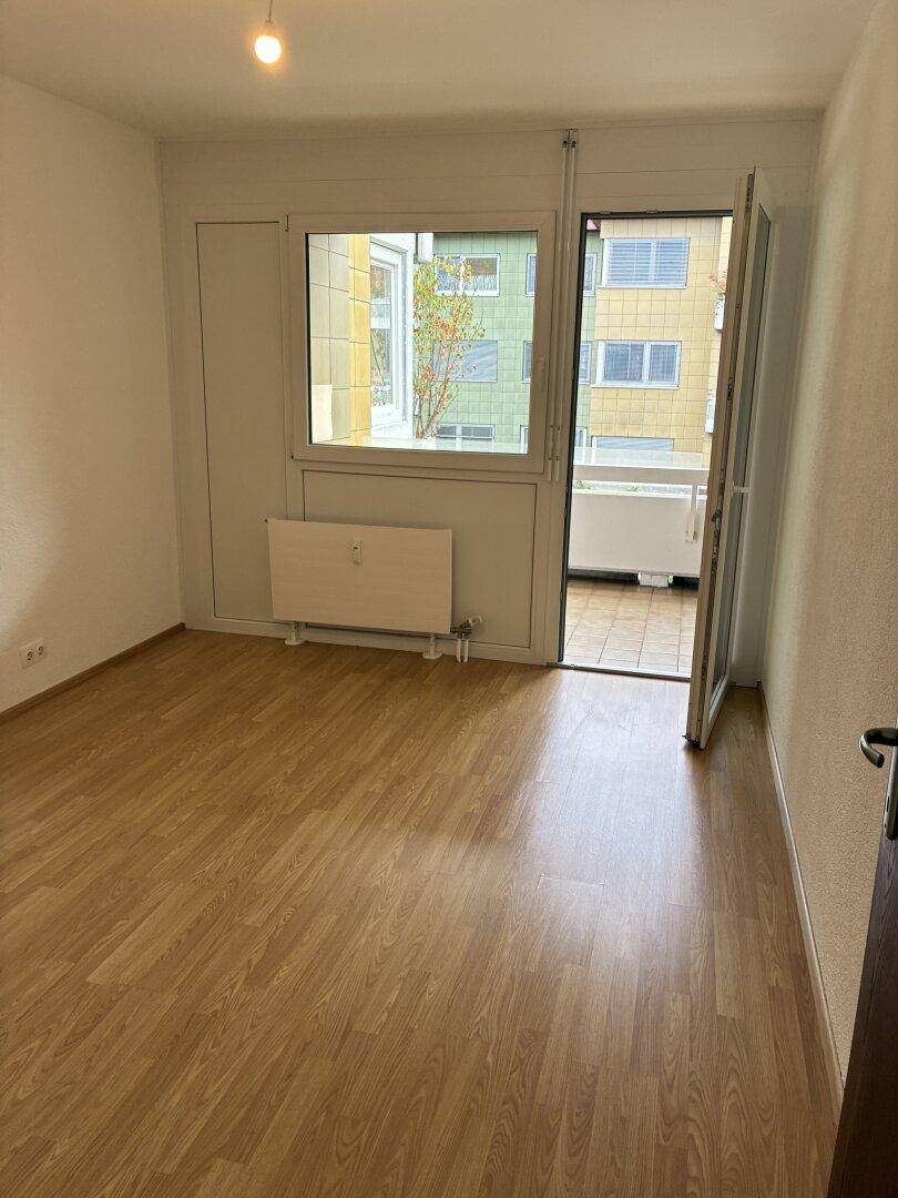Helles Zimmer mit Laminatboden und Zugang zu einem kleinen Balkon.