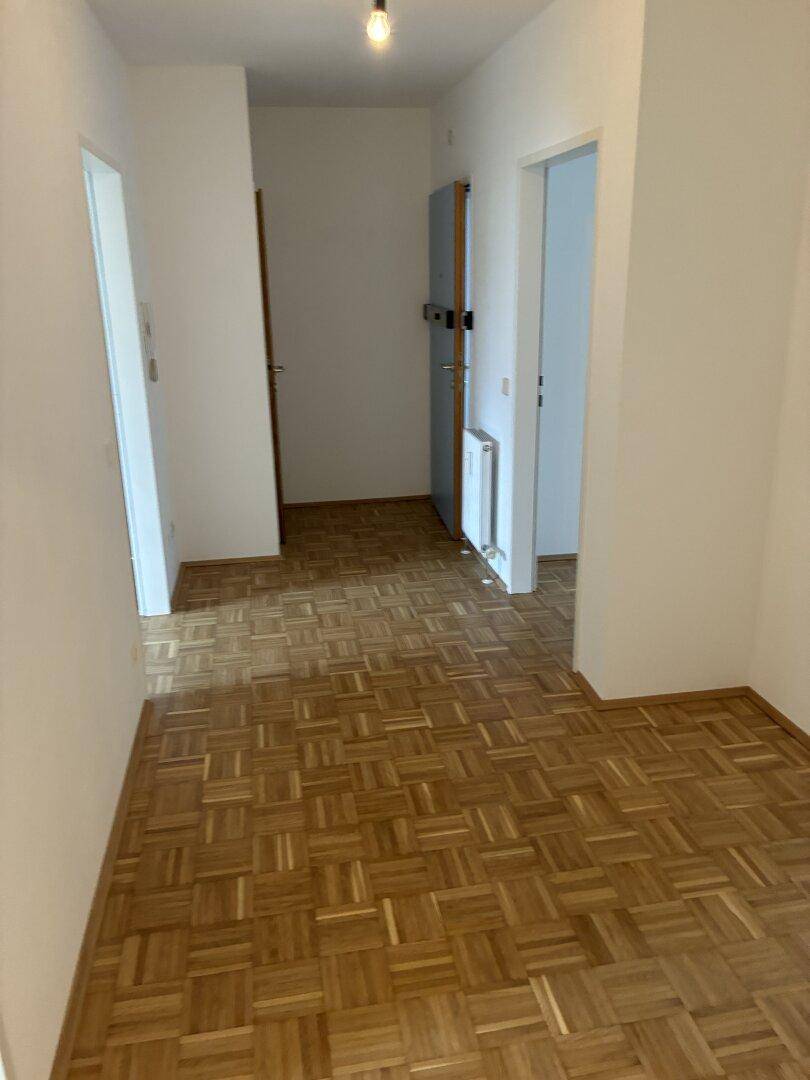 Heller Flur mit Parkettboden und mehreren Türen zu angrenzenden Räumen.