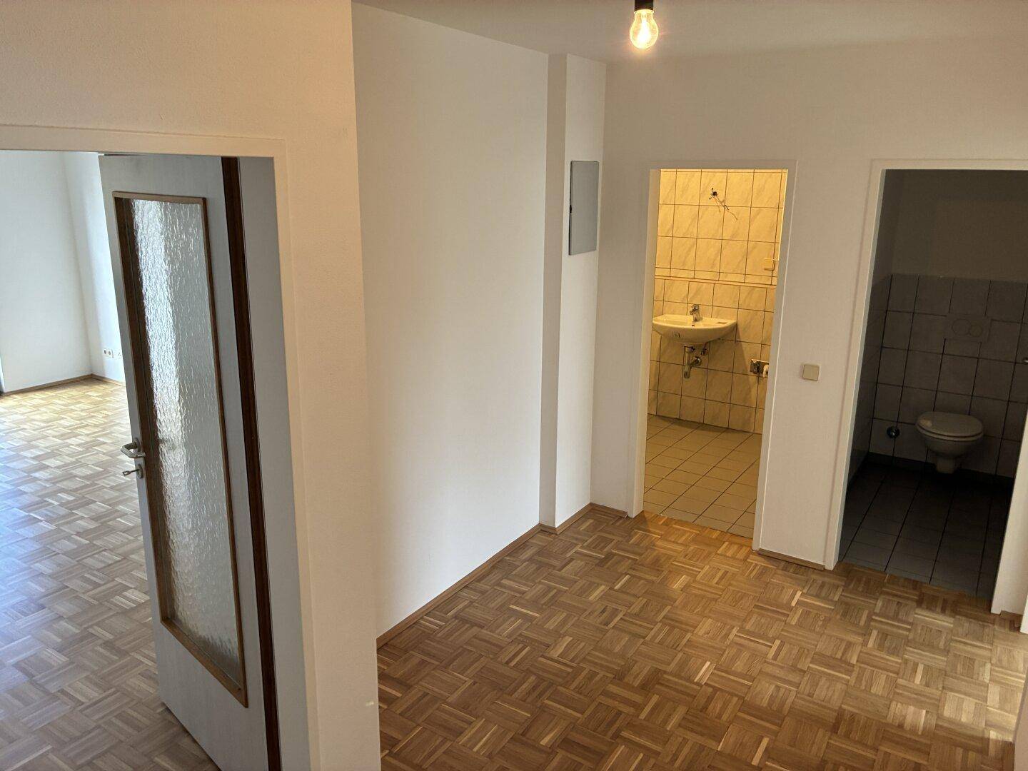 Flur mit Parkettboden und Zugang zu Badezimmer und separatem WC.