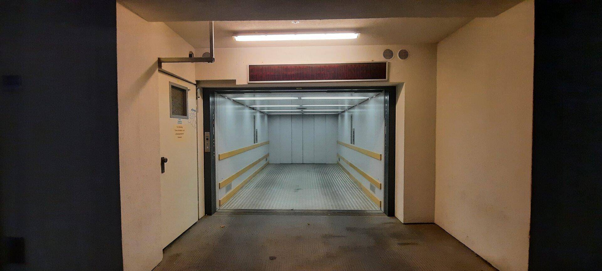 Geräumiger Autoaufzug in einer Tiefgarage, bereit für die Nutzung mit schützenden Seitenwänden.
