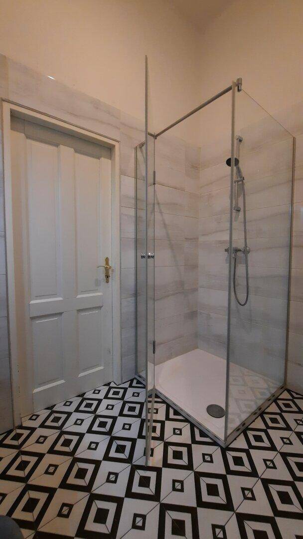 Modernes Badezimmer mit begehbarer Dusche und auffälligen schwarz-weißen Fliesen.