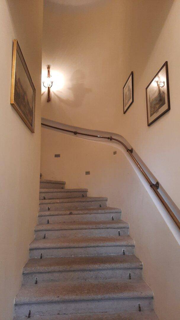 Geschwungene Treppe mit Handlauf und Bildern an der Wand, die in die oberen Stockwerke führt.