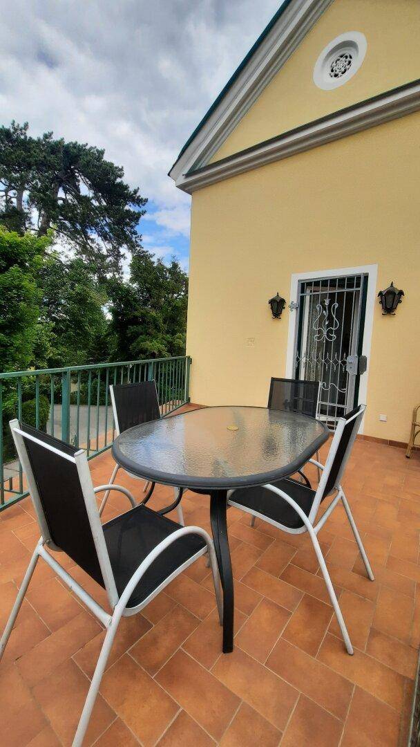 Geräumige Terrasse mit Esstisch und Stühlen, ideal für Mahlzeiten im Freien.