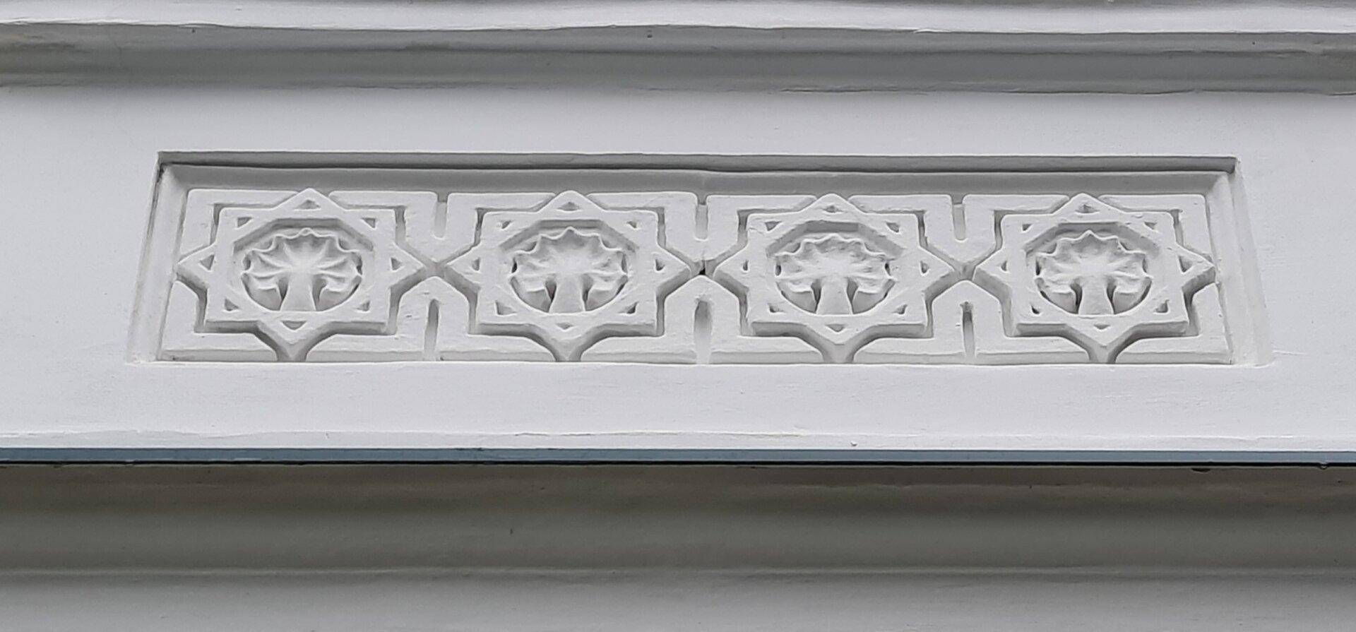 Detailaufnahme einer kunstvollen Stuckverzierung an der Fassade des historischen Gebäudes.